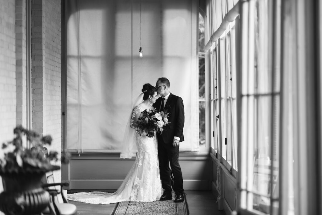 A black and white photo of a newly wed couple posing for a wedding photoshoot inside of a screened porch